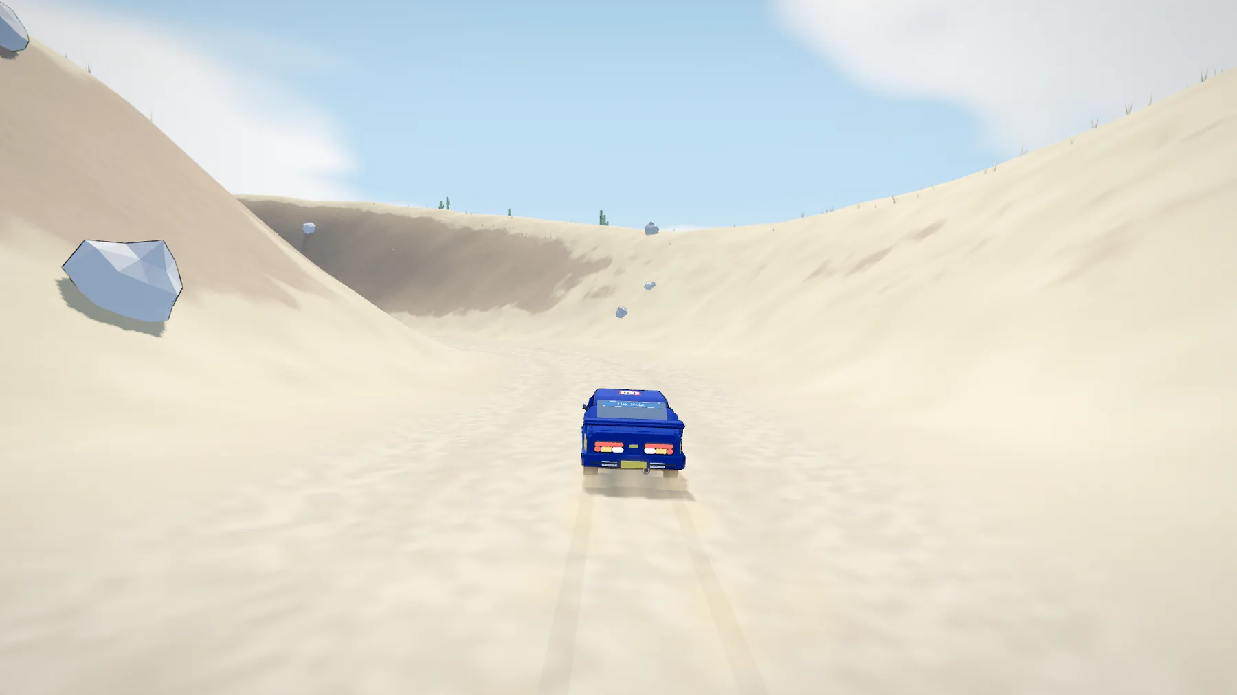 A sand road between tall dunes under a clear sky.